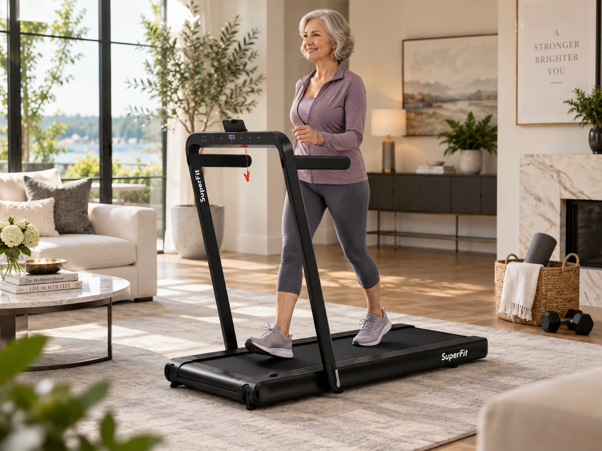 A woman jogging on a black SuperFly foldable treadmill in a bright, modern living room with large windows, a fireplace, and a sofa.